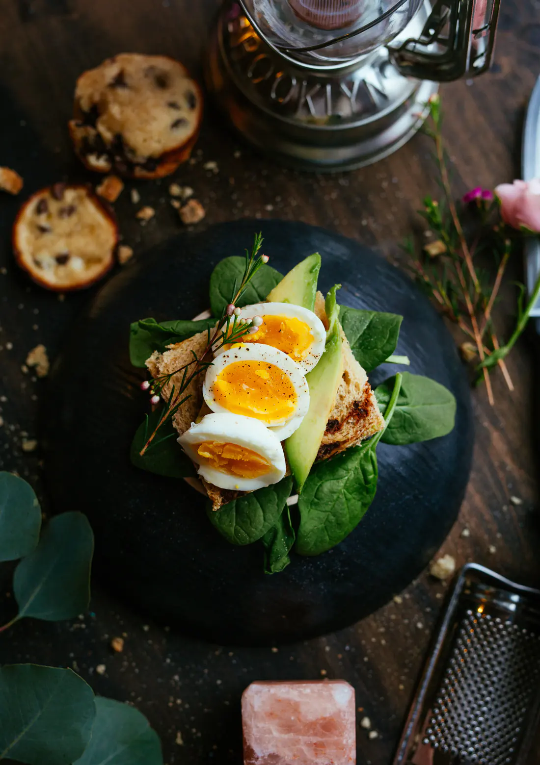 Ein mit Ei, Avocado und Salat belegtes Brot auf einem schwarzen Teller