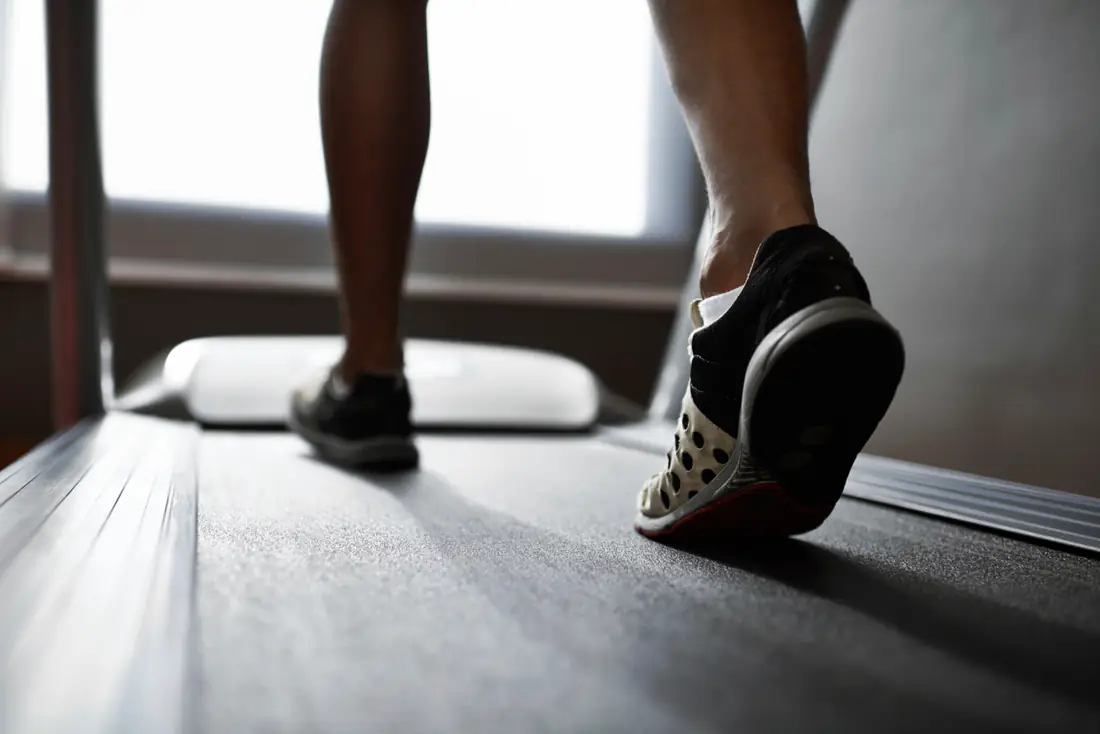 Nahaufnahme von Beinen und Laufschuhen auf einem Laufband