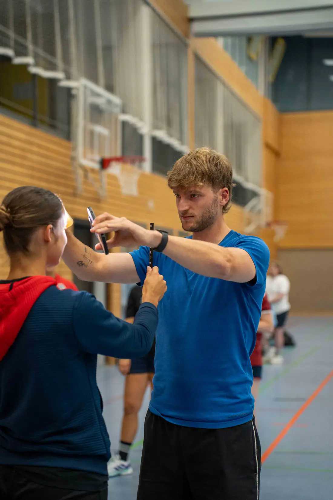 Patrick Keicher führt in einer Sporthalle einen Sehtest mit einer Sportlerin durch